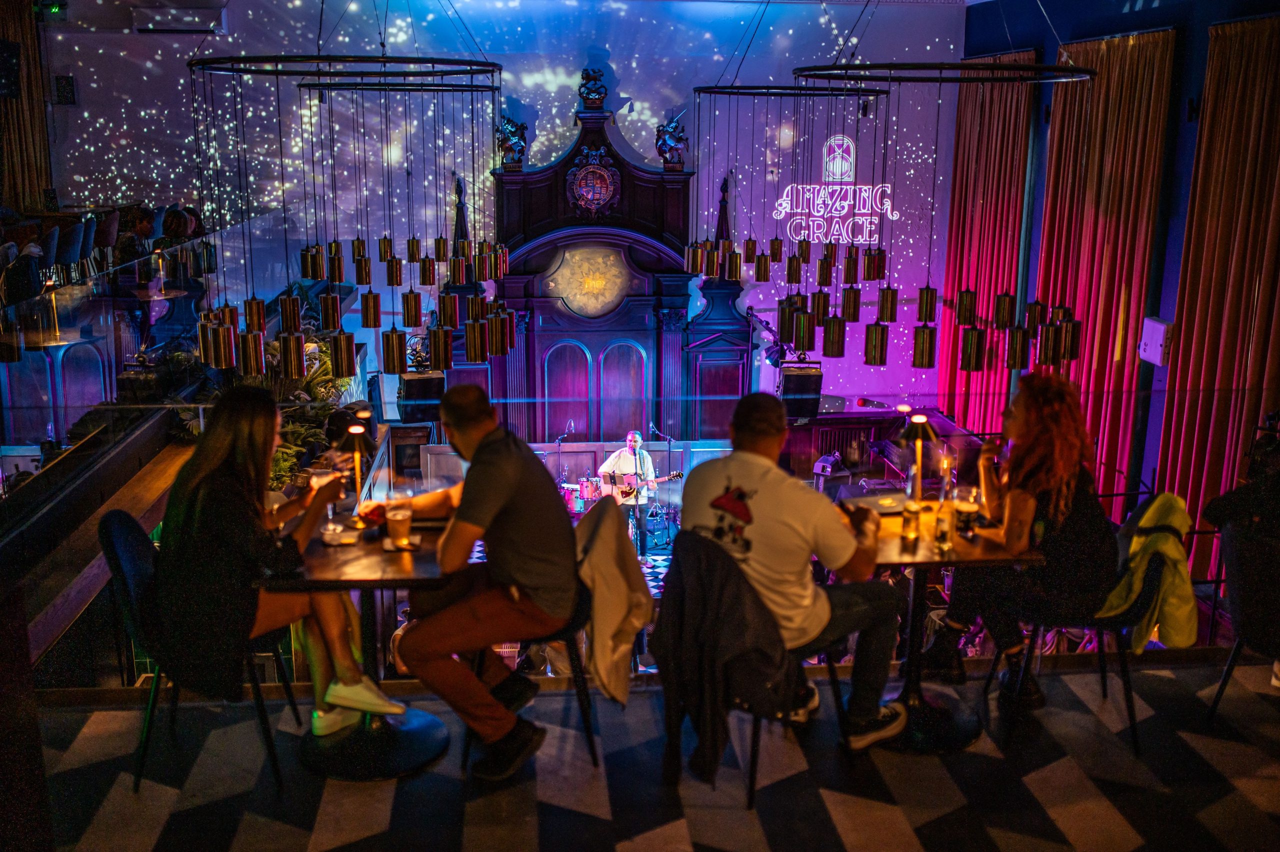 Guests dining at Amazing Grace London Bridge with a live acoustic guitarist performing on stage